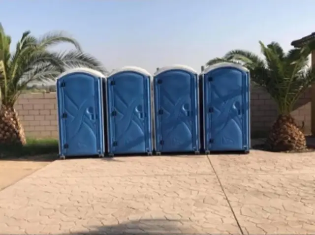 Row of portable toilets lined up side by side for an outdoor event