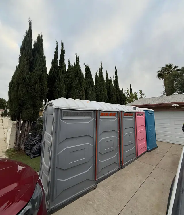Row of portable toilets standing on a paved driveway