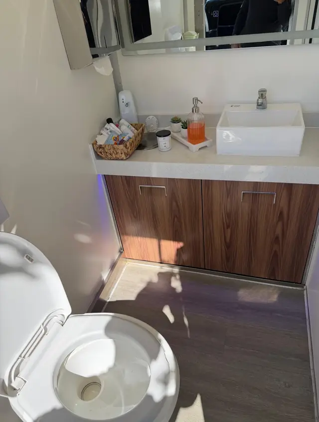 Restroom trailer interior with a wood vanity, sink and mirror