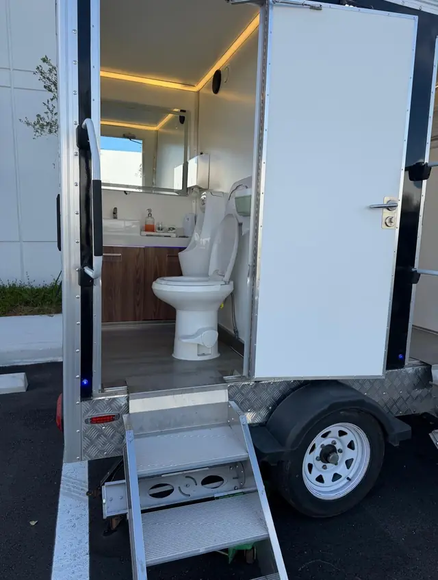 Restroom trailer stall with a wood vanity, sink and mirror