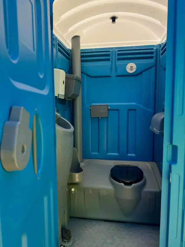 Inside a standard portable toilet with toilet paper and sanitizer dispensers