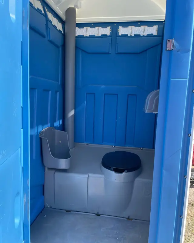 Inside a standard portable toilet with a urinal and toilet seat